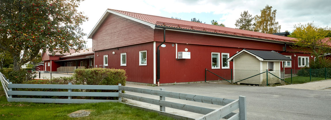 Röd träbyggnad, framför byggnaden är det ett trästaket.